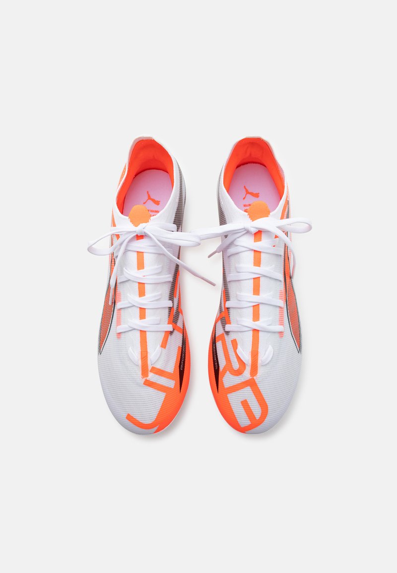 Baskets de sport blanches avec des accents orange et des détails à motifs. Présentent des lacets, une surface texturée et des éléments noirs contrastants.