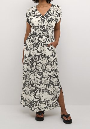 Maxikleid mit Blumenmuster in Schwarz und Weiß, mit V-Ausschnitt, kurzen Ärmeln, geraffter Taille, seitlichen Taschen und Seitenschlitzen für mehr Bewegungsfreiheit.