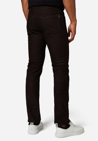 Donkerbruine slim-fit broek met vijf zakken, een zachte textuur en subtiele details. Gekocht met witte sneakers en een zwart top.