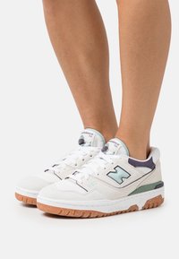 Vita sportskor i texturerat läder, med kontrasterande mintgröna och mörka accenter, rundad tå och gummisula i färgen gummi.