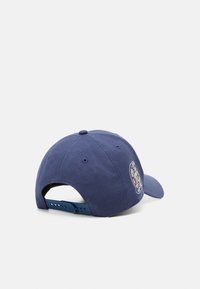Dunkelblaue Mütze mit verstellbarem Kunststoffband, gebogenem Schirm und gesticktem Logo-Patch an der Seite. Baumwollmaterial mit strukturiertem Finish.