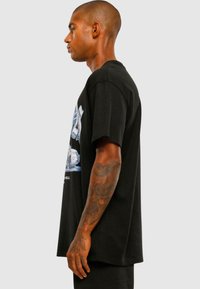 Black cotton t-shirt featuring graphic print on the front, short sleeves, and a relaxed fit, showcasing a seamless design.