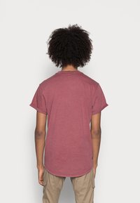 Bordeauxkleurig T-shirt met korte mouwen en een ronde zoom, met opgerolde mouwen, gemaakt van zachte stof, gezien vanuit de achterkant. Zichtbare textuur en pasvormdetails.