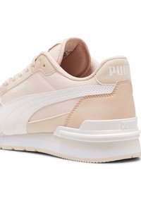 Světle růžová a bílá běžecká obuv Puma z pohledu zezadu, ukazující branding, odpružení paty a detaily struktury podrážky.