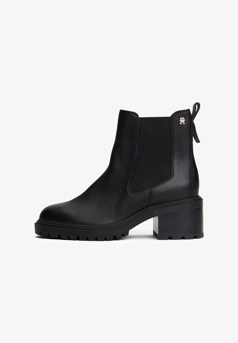 Bottine en cuir noir avec talon chunky, panneau latéral élastique, languette de tirage et petit logo doré près du haut.