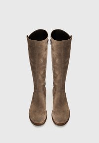Botas de ante marrón hasta la rodilla con una textura suave, punta redonda y cremalleras laterales; diseño simple y aerodinámico sin adornos.