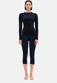 Figurbetontes Sport-Outfit in dunkelblau, mit langen Ärmeln und knielangen Leggings, die texturierte Akzente an den Hosenbeinen aufweisen.