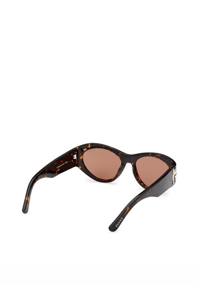 Brune skildpaddeskal katteøje-solbriller med brune linser og sølvfarvet dekorativt emblem på det ene stangben.