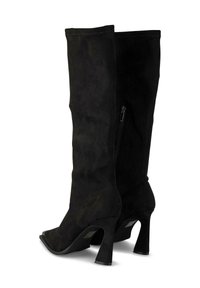 Botas de piel de ante negras hasta la rodilla con punta afilada y tacón cónico, que cuentan con un cierre lateral y una textura suave.