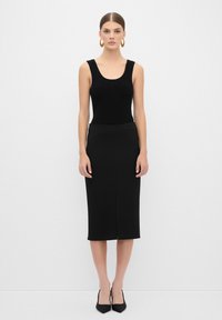 Débardeur noir à côtes associé à une jupe crayon noire arrivant aux genoux. Les deux vêtements présentent un design épuré et minimaliste sans motifs.