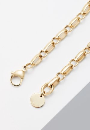 Collier chaîne en or avec des maillons rectangulaires, un fermoir mousqueton à une extrémité et un pendentif rond gravé de "HILFIGER" à l’autre extrémité.