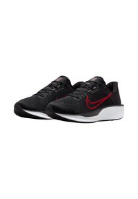 Zapatillas deportivas negras con parte superior texturizada, acentos rojos y entresuela blanca. Presentan una puntera redondeada y suela de goma para tracción.