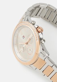 Reloj en tono oro rosa y plateado con una esfera texturizada, subesferas, acentos de cristal alrededor del bisel y una pulsera de metal pulido.