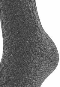 Dunkelgraue Socke aus strukturiertem Stoff, mit einem dezenten Muster und einer figurschmeichelnden Form, die Ferse und Knöchel betont.