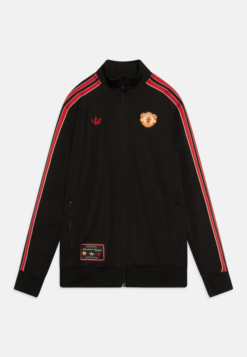 Giacca a vento nera con accenti rossi, chiusura con zip, colletto alto, logo Adidas, emblema del Manchester United e tasche laterali. Texture del tessuto morbida.
