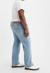 Jeans in denim blu chiaro con una vestibilità dritta, caratterizzati da una patch in pelle sul retro e un dettagli di cucitura discreta sulle tasche posteriori.