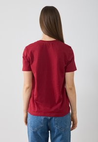 T-shirt rouge à manches courtes avec un col rond, en coton doux, présentant une coupe décontractée et des coutures minimales au dos.