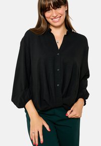 Black button-up blouse with a loose fit, long sleeves, and a V-neckline, featuring a gathered hem and smooth fabric texture.