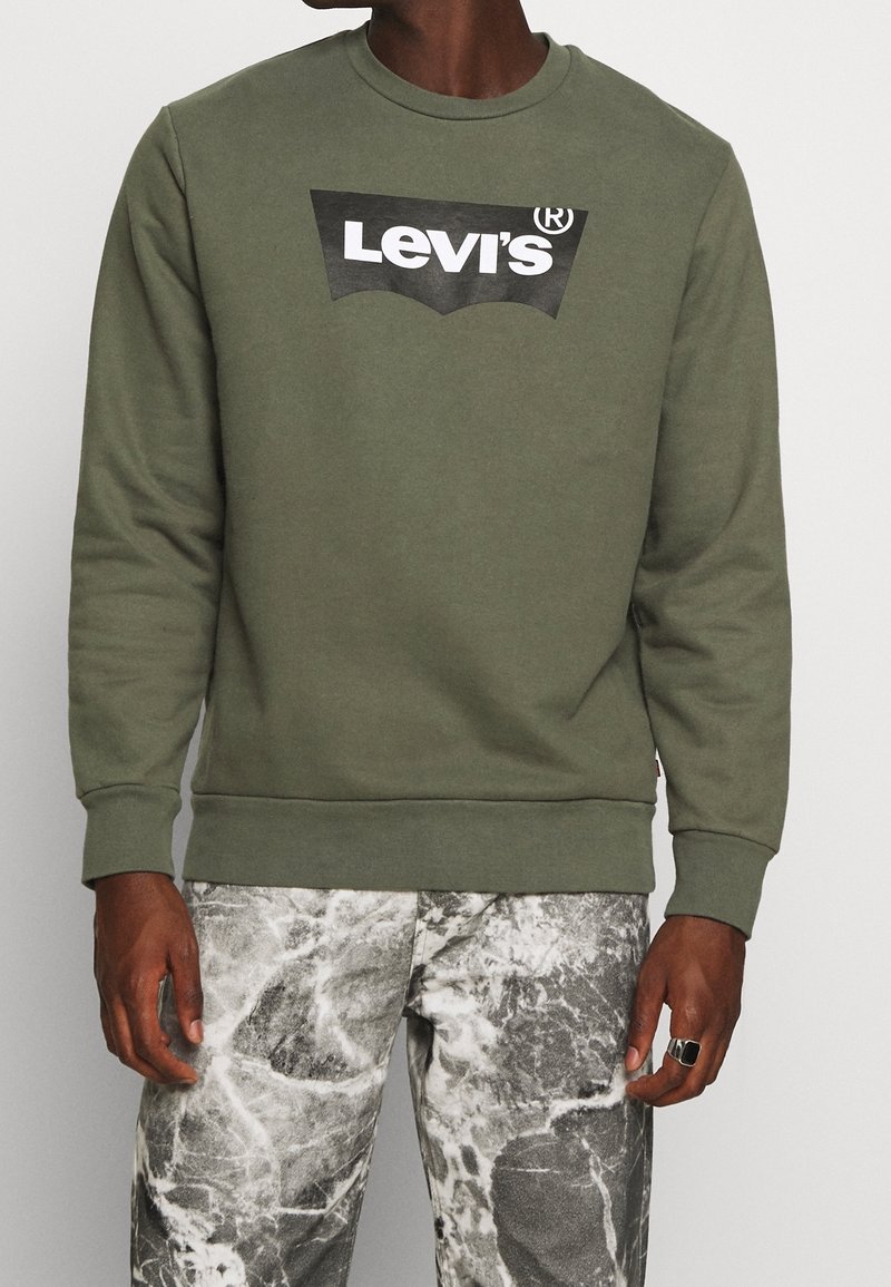 Sweatshirt en polaire vert olive avec un col rond et des poignets côtelés, arborant un logo noir Levi's sur la poitrine. Tissu texturé.