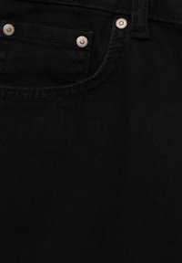 Jean de mezclilla negro con un bolsillo frontal adornado con remaches de metal plateado y detalles de costura en contraste. Textura suave, ajuste clásico.