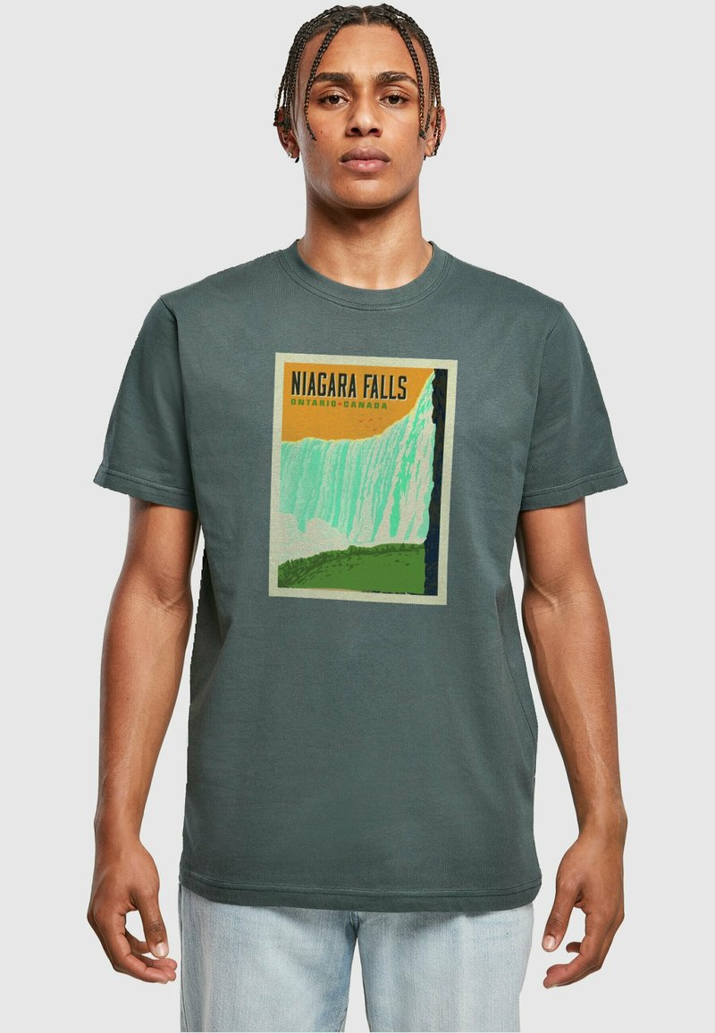 Σκούρο πράσινο βαμβακερό t-shirt με γραφικό τύπωμα του καταρράκτη του Νιαγάρα με κίτρινες και πράσινες λεπτομέρειες. Στρογγυλή λαιμόκοψη; κοντά μανίκια.