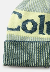 Világos zöld és halványkék kötött sapka bordás textúrával; sötétzöld szöveggel és mintákkal díszítve. Felhajtott kialakítás a biztonságos illeszkedésért.