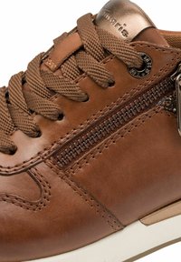 Ruskean nahka-sneakerit, joissa on teksturoitu pinta, pyöreä kärki ja edestä nauhoitettava malli. Mukana sivuvetoketju ja metalliset yksityiskohdat.
