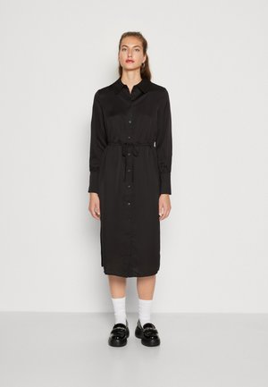 Black midi dress with long sleeves, collared neckline, button front, drawstring waist, and smooth texture. Paired with black loafers and white socks.