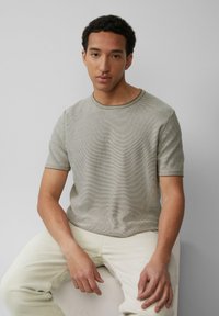 Korte mouwen, lichtgrijze gestreepte T-shirt met een ronde halslijn, textuurstof, gecombineerd met lichte broek.