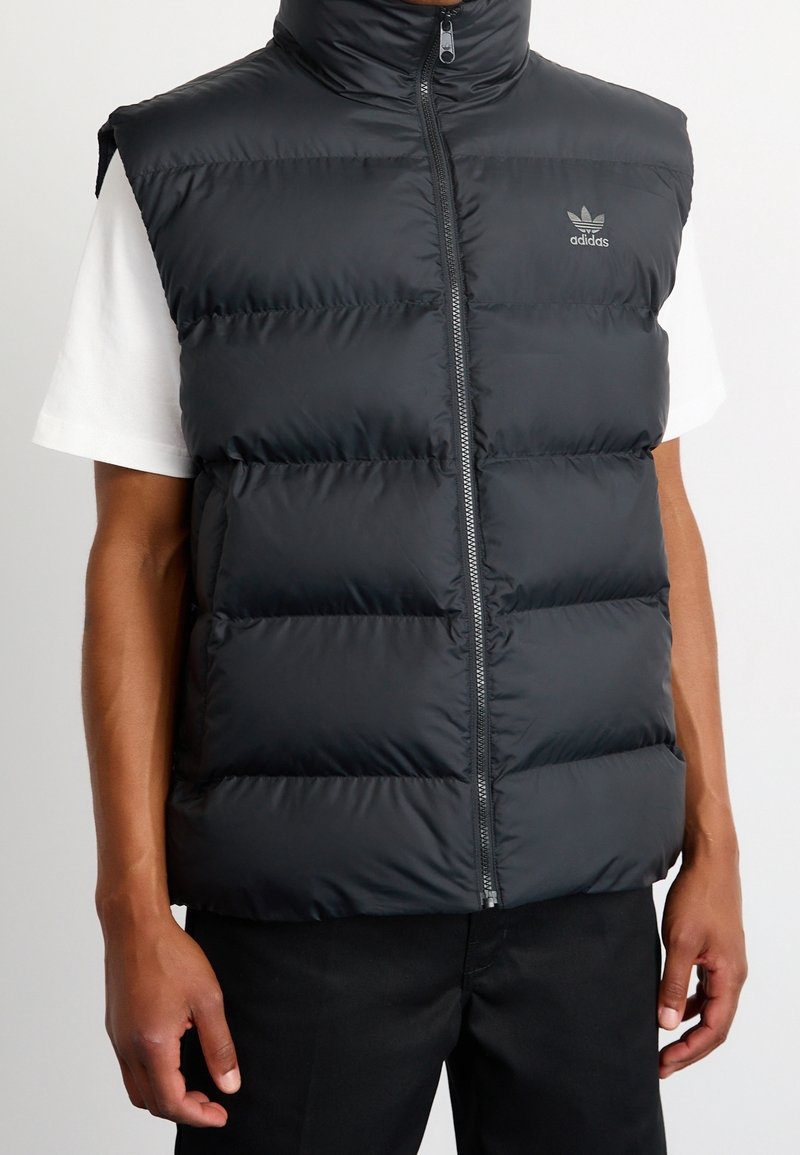 Svart ärmlös puffer-väst i glänsande material, med hög krage, dragkedjestängning och horisontell quiltad design med logotyp.