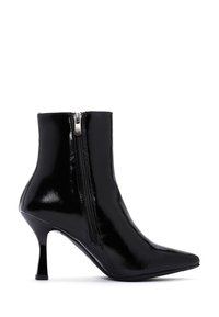 Stivale alla caviglia in pelle verniciata nera con punta appuntita, tacco medio e zip laterale. La texture liscia e la silhouette elegante accentuano il suo design.