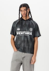 Polo negru cu mânecă scurtă și un model subtil în valuri, dotat cu guler, accente albe și logo-ul "VENTURA" pe față.
