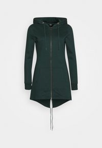 Sudadera larga verde hecha de material suave, con un cierre en la parte delantera, capucha con cordón y bolsillos laterales. El dobladillo está redondeado en la parte trasera.