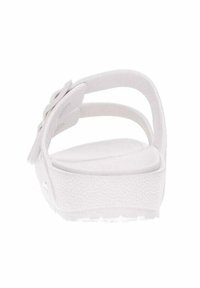 Sandali bianchi con suola testurizzata, punta arrotondata e design con cinghie incrociate. Materiale morbido per il comfort, caratterizzati da uno stile minimalista.