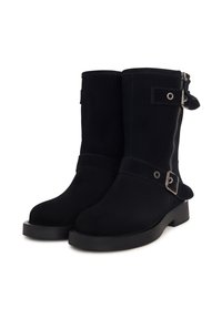 Botas negras de tobillo hechas de ante, con cremallera lateral, tira con detalle de hebilla y suela de goma gruesa. Textura suave en general.