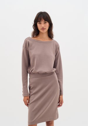 Pikkade varrukatega, mauve värvi lahtine pluus, millel on paigaldatud kaelus, koos sobiva liibuva midi seelikuga. Pehme, siledatud kangas minimaalsete detailidega.