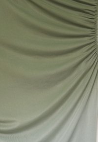 Olivengrüner Stoff mit einer sanften, glatten Textur und gerafften Details an einer Kante, die einen drapierten Effekt erzeugt.