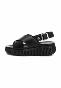Sandalias de plataforma negras con un diseño de tiras cruzadas, hechas de cuero suave. Suela texturizada y correa ajustable en el tobillo con hebilla de metal.