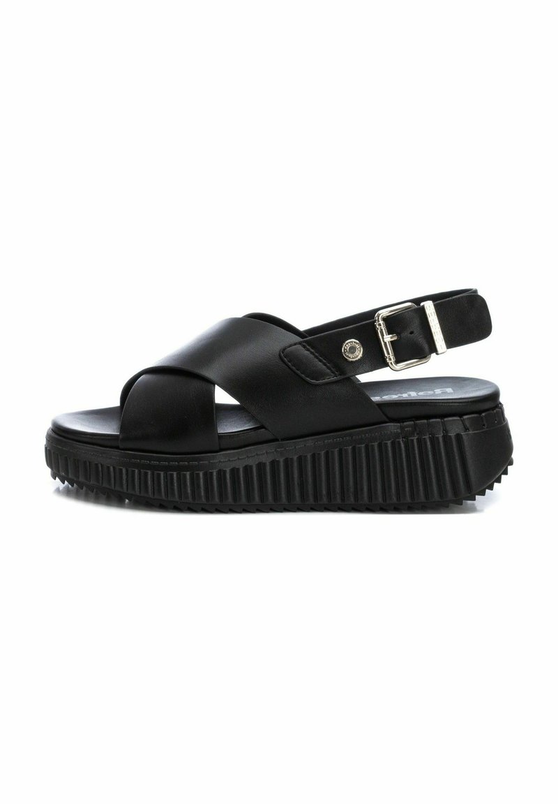 Sandalias de plataforma negras con un diseño de tiras cruzadas, hechas de cuero suave. Suela texturizada y correa ajustable en el tobillo con hebilla de metal.