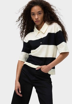 Poloshirt met korte mouwen in crèmekleur met zwarte strepen, van katoen, met een puntkraag en knoopsluiting. Gemaakt met zwarte broek.