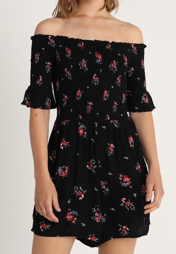 Rompers noir décolleté avec un motif floral, corsage smocké, manches courtes et ourlet froncé. Tissu léger et fluide ; design décontracté.
