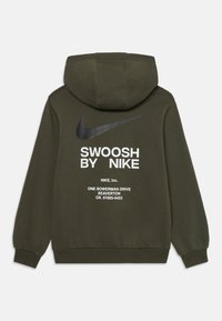 Mørk grønn hettegenser med svart Nike-svobb og hvit tekst "Swoosh by Nike" og adresse trykt på baksiden.