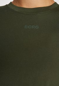 Zaļš, īsām piedurknēm T-krekls ar apaļu kakla izgriezumu un diskrētu "BORG" logotipu atbilstošā zaļā tonī uz krūtīm. Mīksta auduma tekstūra.