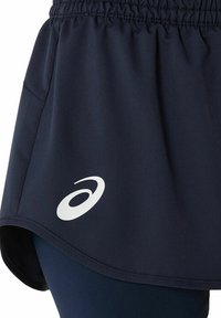 Jupe de sport marine en tissu lisse, avec une taille élastique. Comprend un logo blanc sur l'ourlet gauche.