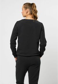 Svart sweatshirt med långa ärmar och rund halsringning, tillverkad av mjukt bomullstyg. Har ribbade muddar och nederkant. Slät, enfärgad textur.