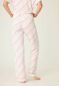 Lehké pyžamové kalhoty vyrobené z bílé látky s růžovým a červeným srdíčkovým vzorem, se střihem rovného nohavice a kotníkovou délkou zakončenou jemným střihem.