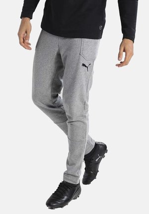 Graue sportliche Sweatpants mit elastischen Bündchen, seitlichen Taschen und einem schwarzen Puma-Logo am Bein, kombiniert mit schwarzen Sportschuhen.