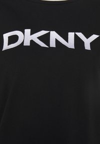 Černé tričko má velké vyšívané bílé logo "DKNY". Materiál je hladká bavlna s designem kulatého výstřihu. Jednoduchý a minimalistický styl.