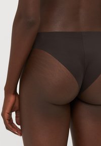 Smeđi bikini donji dio od tkanine s elegantnom, glatkom teksturom; nisko sečeni dizajn koji prikazuje minimalan izrez straga i sa strane.