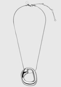 Collier en argent avec un pendentif en forme de cœur lisse et irrégulier. Le pendentif présente une finition polie et un design central ouvert.